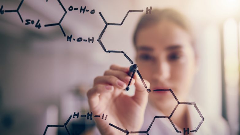 Shot of a focused young female scientist solving equations on a glass wall in a laboratory